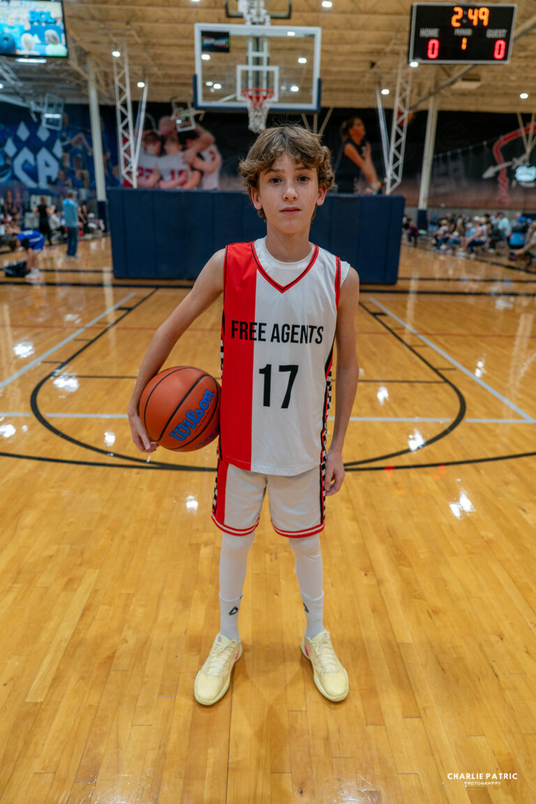 A young basketball player in a "Free Agents" jersey with the number 17 stands on an indoor court holding a basketball, perfect for sports photography for college recruitment.